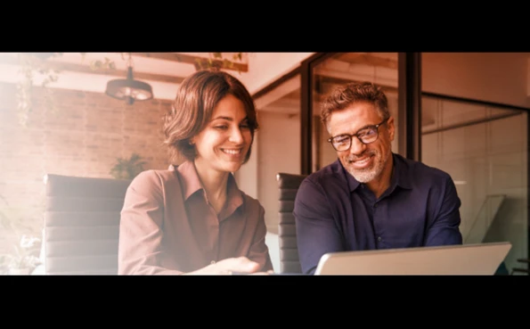 Two professionals working together on a laptop to implement cybersecurity measures for business data protection.