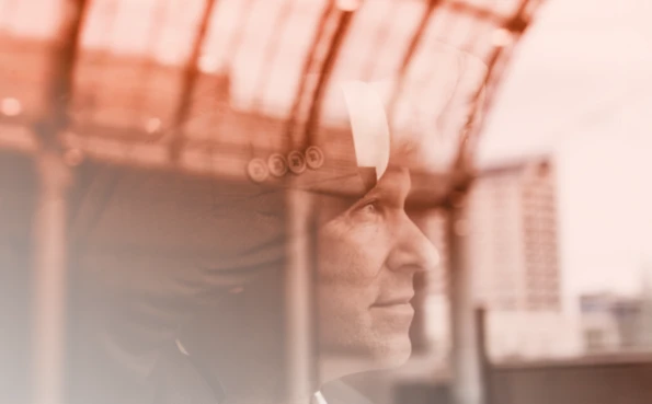 Primo piano laterale di un uomo d'affari in giacca e cravatta che osserva fuori da una finestra, simboleggiando strategia e visione.