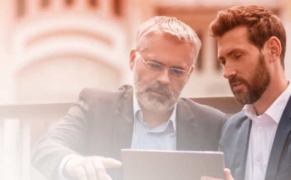 Due professionisti collaborano e analizzano dati su un dispositivo digitale.