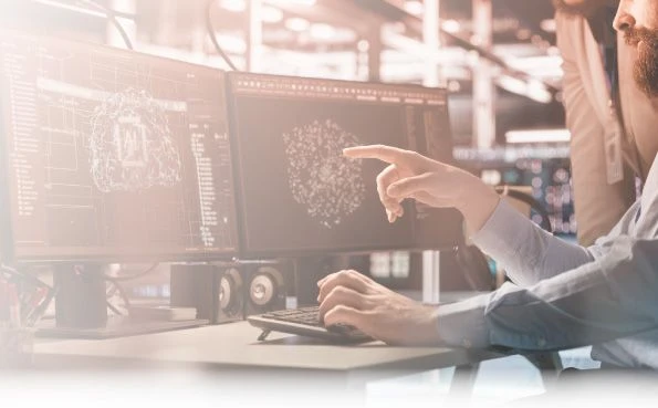 Due professionisti di dati collaborano su un computer con due monitor, analizzando modelli 3D di dati complessi e applicazioni di intelligenza artificiale.