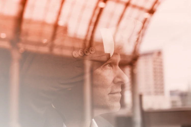 Close-up side view of a businessman in a suit and tie looking out of a window, symbolising strategy and vision.