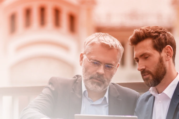 Two professionals collaborate and analyse data on a digital device.