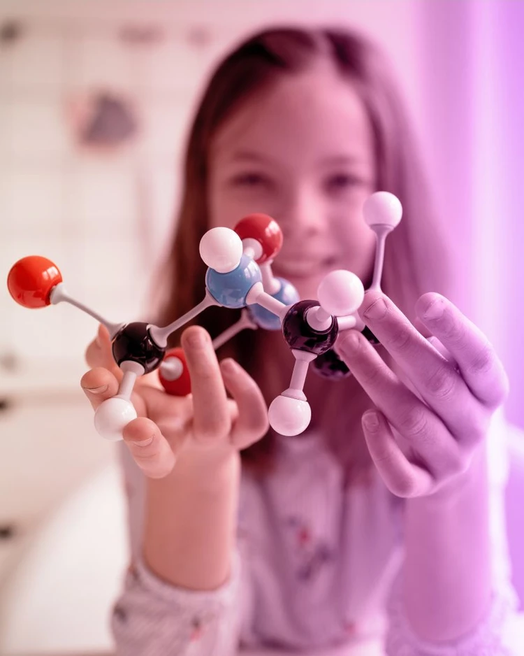 Una bambina gioca con un modellino di molecola.