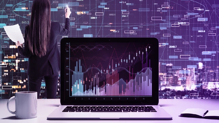 An analyst interacting with a digital data wall while a foreground laptop renders complex analytics, showcasing the synergy between data & ai in corporate workflows.