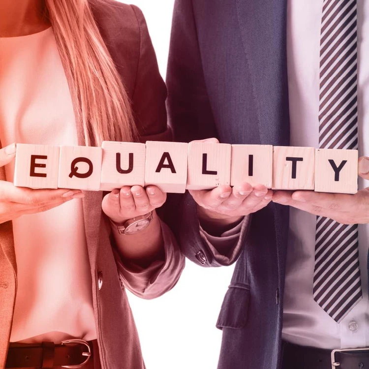 A close-up of a man and a woman holding wooden blocks that spell out 'Equality', representing equality in the workplace.