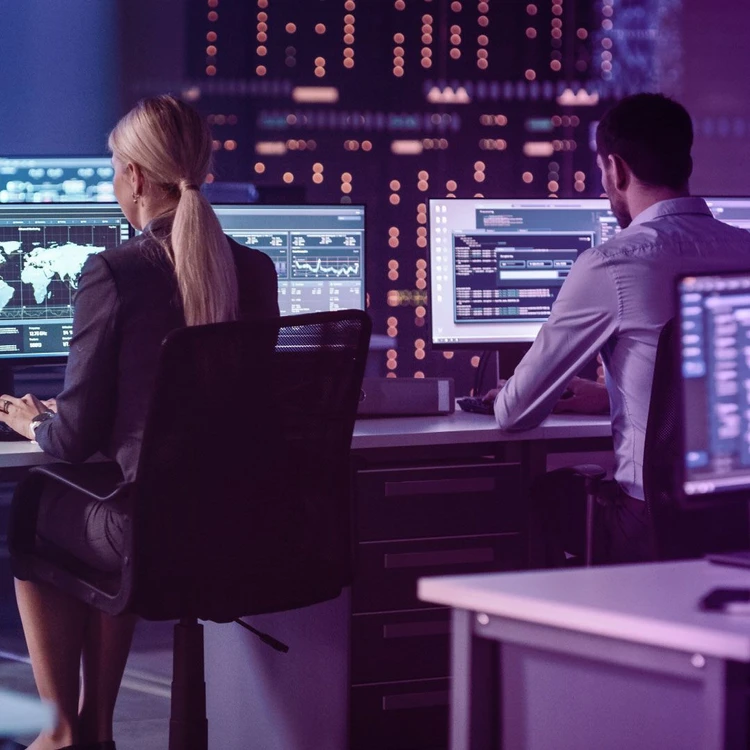 Un uomo e una donna, seduti nella loro postazione in ufficio, guardano i monitor dei pc.