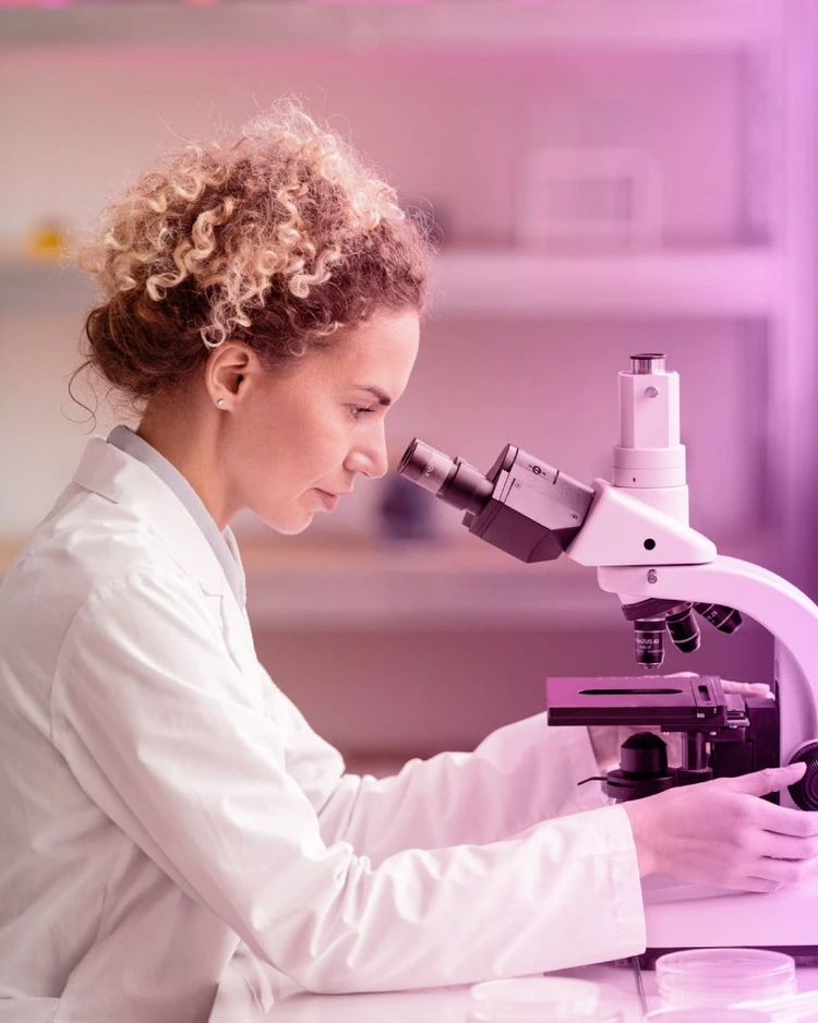 Una ricercatrice guarda attraverso un microscopio.